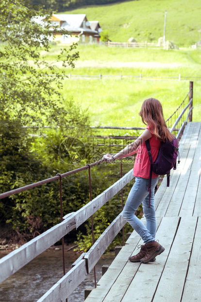 青年女孩背着包徒步旅行在山地和森林之间图片