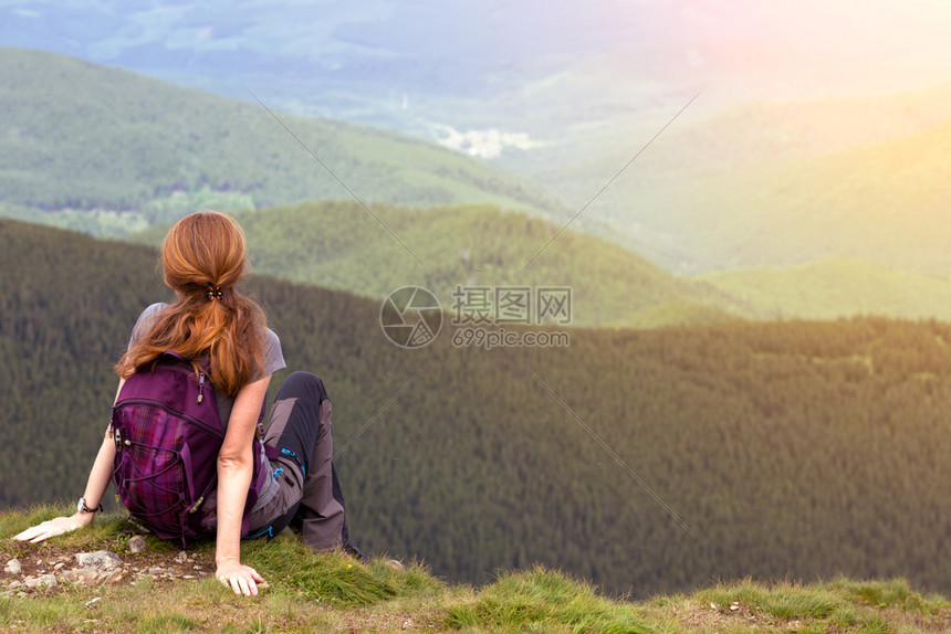 青年女孩背着包徒步旅行在山地和森林之间图片