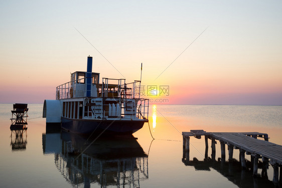 在日落时以船和码头在前方的海景图片