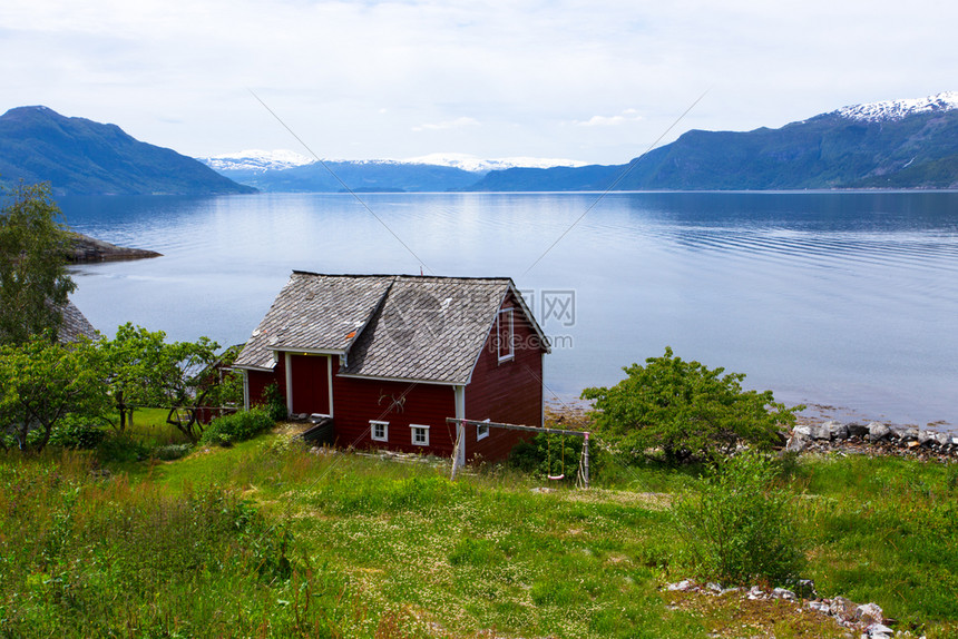 在峡湾海岸的红挪威农村住宅图片
