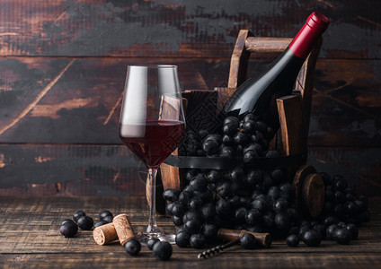 黑色的红葡萄酒和古老的木桶里葡萄酒深黑木质背景红酒保留生命的概念图片