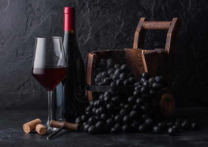 高雅的玻璃和一瓶红色葡萄酒有古老的木桶内深葡萄底黑色石块图片
