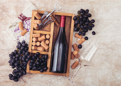 瓶装红酒和空玻璃有深葡萄软塞和开瓶器装在旧木箱内以浅本底带亚麻毛巾图片