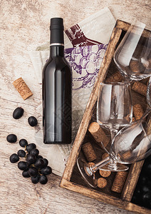 瓶装红酒和空玻璃黑葡萄装有软瓶和开器用木制盒装有皮巾图片