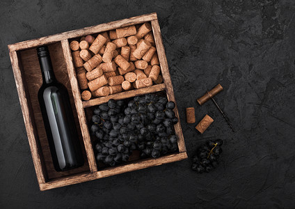 酒瓶红黑葡萄色背景的旧木箱里装有软塞和开瓶器图片