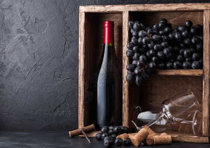 瓶装红酒和空杯子在旧的木箱内用深葡萄黑石头背景瓶装和黑板上的装子图片