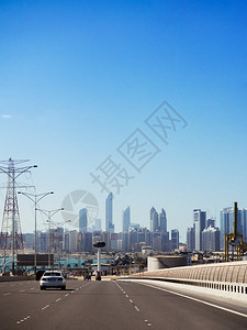 在蓝色夏日天空下乘摩大楼的横越阿布杜海市中心上空的高速公路轻型汽车交通图片