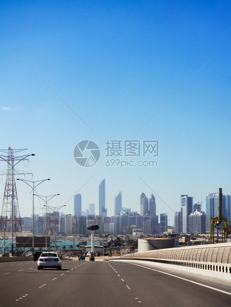 在蓝色夏日天空下乘摩大楼的横越阿布杜海市中心上空的高速公路轻型汽车交通图片