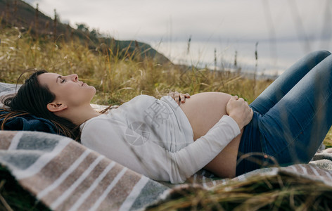 孕妇在草地上抚摸肚子图片