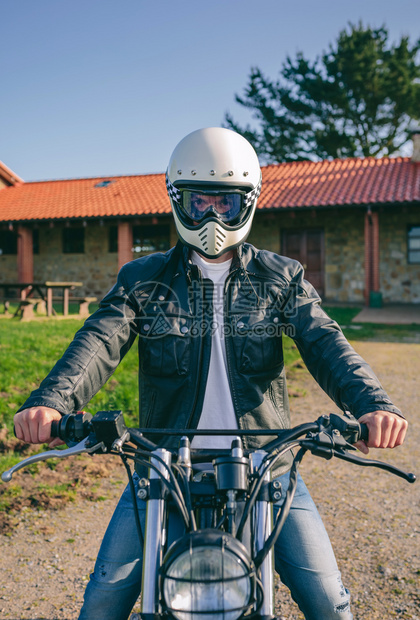 戴头盔的年轻人在户外特制摩托车上骑着头盔的普通摩托车