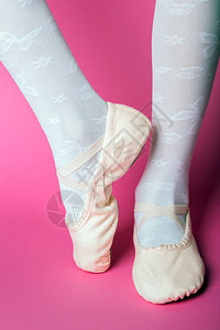 小芭蕾舞者在粉红色背景上用指尖向腿芭蕾舞姿势图片