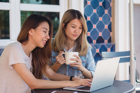 身着智能散装服的亚洲年轻女坐在咖啡馆时用笔记本电脑发送子邮件和喝咖啡生活方式上的妇女交流和从事咖啡店概念方面的工作图片