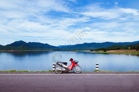 蓝色湖边的古红摩托车公园夏季天空和山丘背景图片