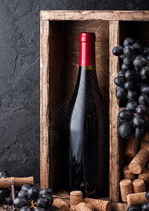 酒瓶红深葡萄和软木塞在旧箱里黑色石头背景图片