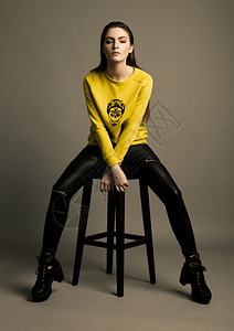 美丽的时装模特黄色跳跃者坐在演播室图片