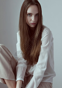 模拟测试采用年轻美时装模特长发灰色背景白衬衫图片