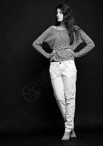 模型测试肖像以年轻的美丽时装模特在灰色背景上跳跃器白牛仔裤图片