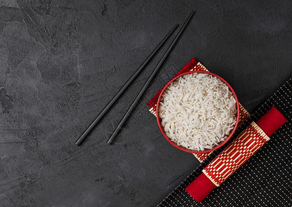 红碗加煮的有机巴斯马提茉米饭竹制地皮上有黑筷子石底有红皮巾图片