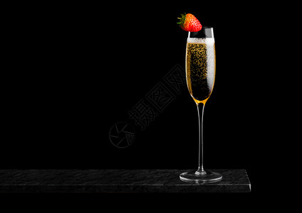 气泡饮料优雅的黄色香槟杯子上面有草莓黑色大理石板上有黑底背景