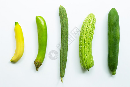 香蕉、绿色长茄子乳酪苦瓜白底绿木。背景图片