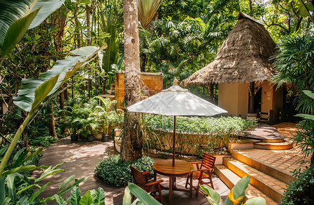 2014年月日泰国克拉比热带花园中雨伞的木椅和桌图片