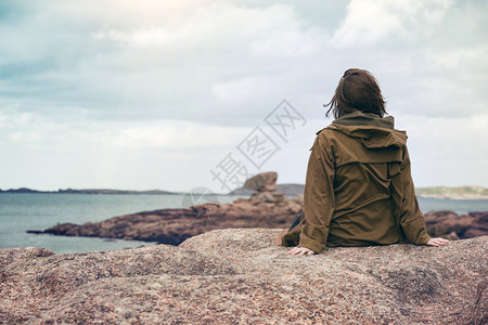 女孩旅行者坐在靠近海边的滩上图片