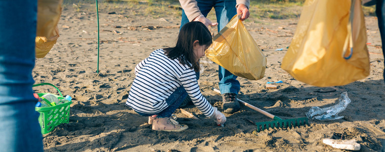 女孩志愿者在海滩上捡垃圾图片