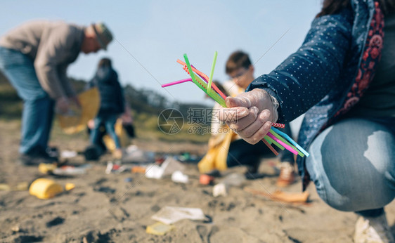 爷爷和孙女志愿者在海滩上拾取塑料吸管图片