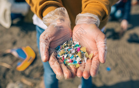 海滩上带有微塑料的手图片