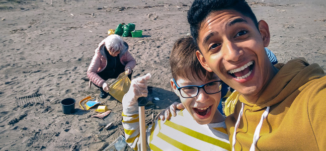 青年男子在清理海滩后与一群志愿者自拍图片