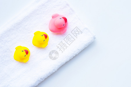 白毛巾上的粉色和黄鸭玩具白背景孩子们洗澡的概念图片