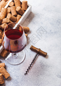 一杯优雅的红葡萄酒里面装着一盒软木和开瓶器放在厨房桌底图片