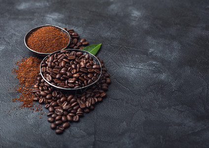 黑色上含地粉和咖啡树叶的新鲜有机咖啡豆文本空间图片