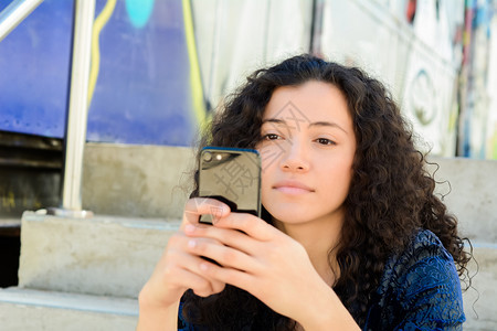 美丽的年轻女子在街上用智能手机发信息图片