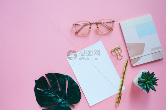 工作空间办公桌平板用带纸笔剪片和眼镜的笔记本短片和眼镜粉色背景和复制空间图片