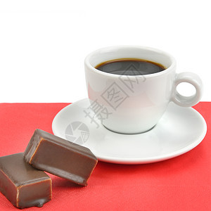 一杯咖啡和巧克力糖果放在一张红色纸巾上白背景的红纸巾上图片