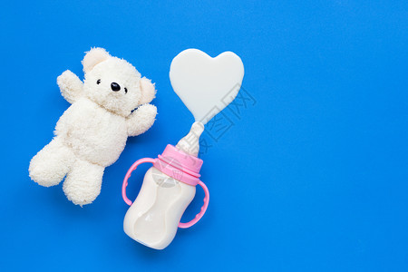 蓝背景的玩具白熊和婴儿奶瓶图片