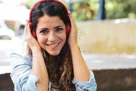 快乐的年轻女子在街上用耳机听音乐夏季生活方式图片