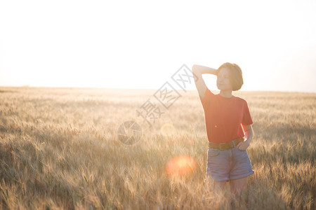 晚上小麦田快乐的年轻女孩日落和大气氛图片