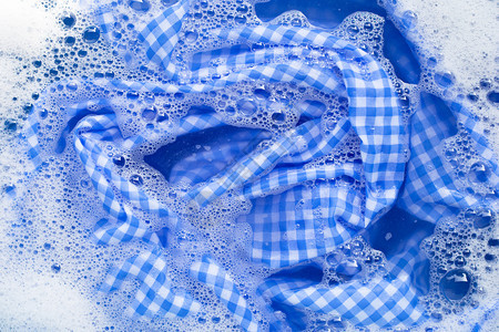 蓝色白桌布浸泡在粉末洗涤水溶解衣服中图片