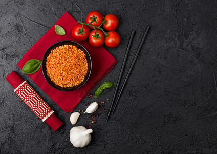 黑盘饭碗有番茄烤肉大蒜和筷子红餐巾竹垫上有红餐巾黑底的竹子垫上有黑底最高视图文本空间图片