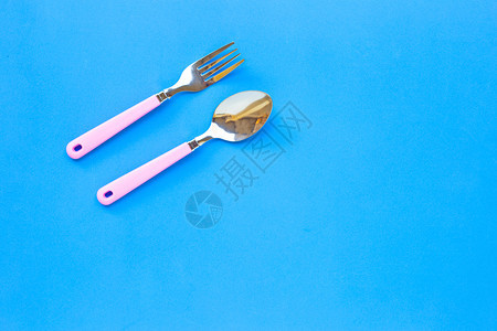 蓝背景上的叉子和勺顶视图图片