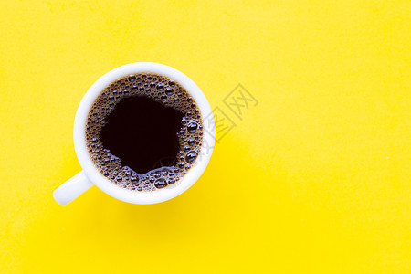 黄色背景的热黑咖啡顶视图图片