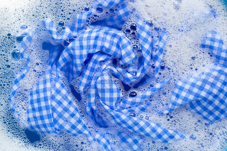 蓝色白桌布浸泡在粉末洗涤水溶解衣服中图片