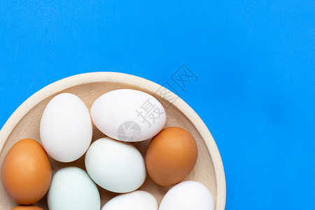 在蓝色背景的鸡蛋上顶部视图图片
