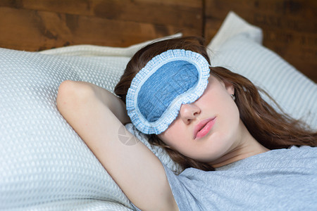 年轻女睡在床上时戴着眼罩图片