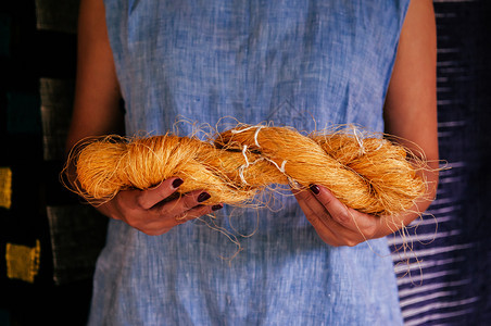 手握着天然黄色丝纤维传统养殖塔伊丝制作的原材料图片