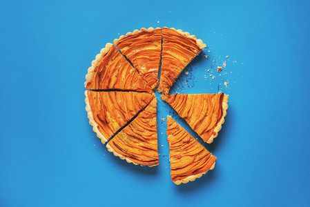一块甜土豆馅饼用碎屑切成一片在蓝纸背景上切成一片美式传统馅饼味的秋天食物图片
