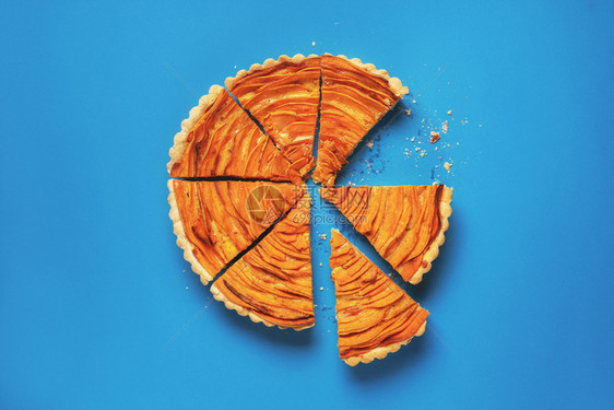 一块甜土豆馅饼用碎屑切成一片在蓝纸背景上切成一片美式传统馅饼味的秋天食物图片