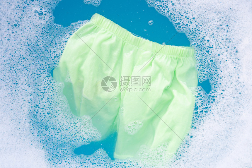 浸泡在婴儿洗衣清洁水溶解洗衣布蓝背景洗衣概念中图片